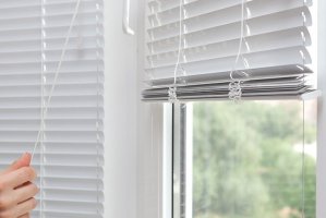 Girls hand raise the white blinds with a cord